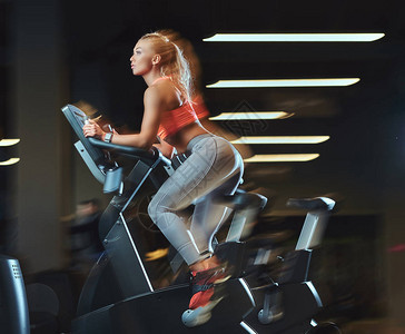 运动金发女郎在现代健身中心骑自行车锻炼图片