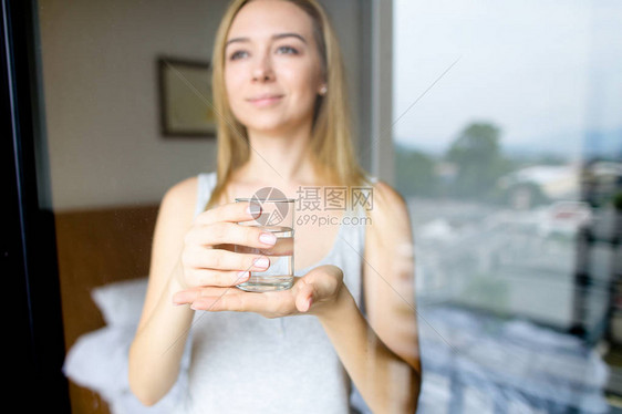 年轻的欧洲女人早上在酒店端着一杯水站着健康生活方式和饮图片