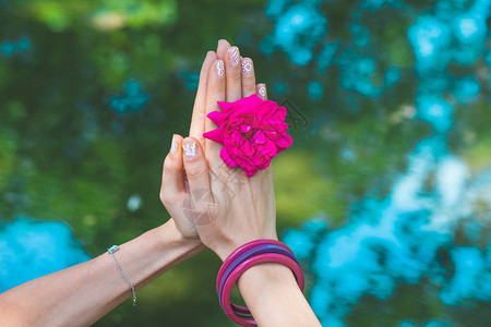 在野外的瑜伽泥浆动作中女人手握花朵在大自然中在图片