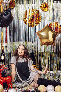 带着金气球明星的耀眼女人坐在一个闪发亮的派对空间里背着金和银装饰图片
