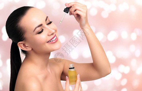 用吸管涂抹在年轻女人脸上的化妆品油的特写镜头美容疗法的概念灯光模图片