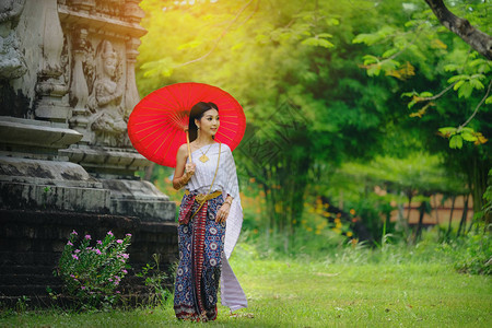 身着传统服饰红伞的美丽泰国女孩作为公共场所的泰国寺庙图片
