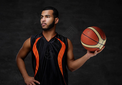 身穿运动服的非裔美国青年篮球运动员在黑暗背景中孤图片