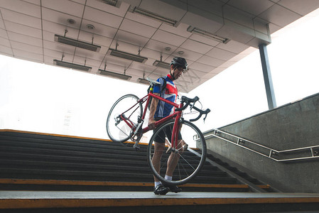 穿着运动服的自行车手拿着自行车从地下通道下楼梯在地铁里骑自行车骑着自图片