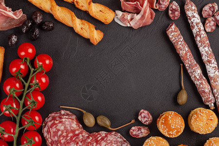 灰色混凝土背景上的迷你汉堡香肠火腿小吃橄榄奶酪品种板和法式面包图片