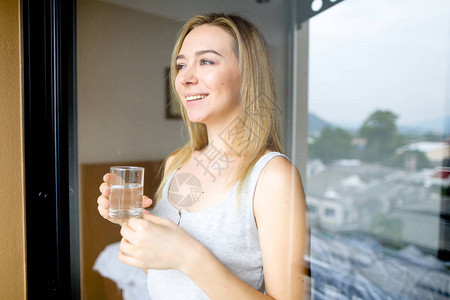 年轻快乐的女早上在酒店喝杯水健康和饮图片
