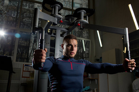 强壮的青年运动员在体育设备上锻炼手臂图片