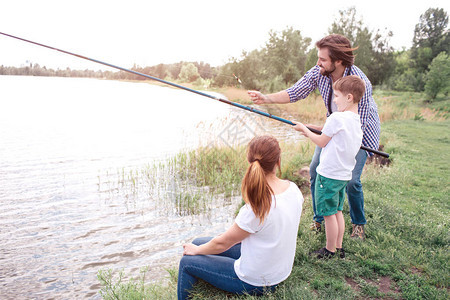 盖伊正在教他的儿子如何正确捕鱼男孩拿着长鱼竿盖伊正在指导他年轻女子图片