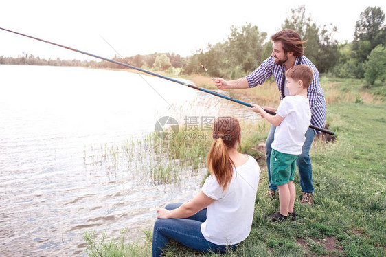 盖伊正在教他的儿子如何正确捕鱼男孩拿着长鱼竿盖伊正在指导他年轻女子图片