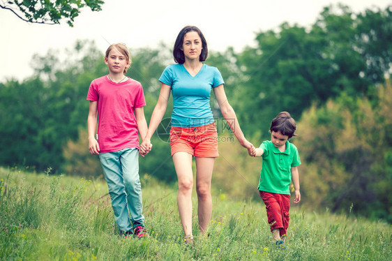 孩子们和他们的母亲一起穿过田野男孩们在绿草丛生的草地上和妈握手一个女人花时间和她的儿子在一起家庭价值观图片