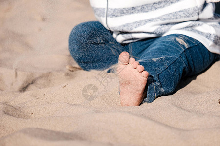 婴儿手在阳光刺眼的沙滩上玩沙子图片