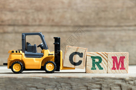 玩具黄色叉车在木材背景上用字母块填全CRM客户关系管理的缩图片