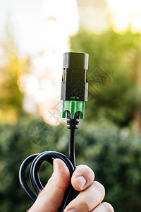 POV在绿色背景电源带与IEC电线连接的绿背景电源条上持图片