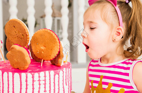 小女孩在生日蛋糕上吹蜡烛图片
