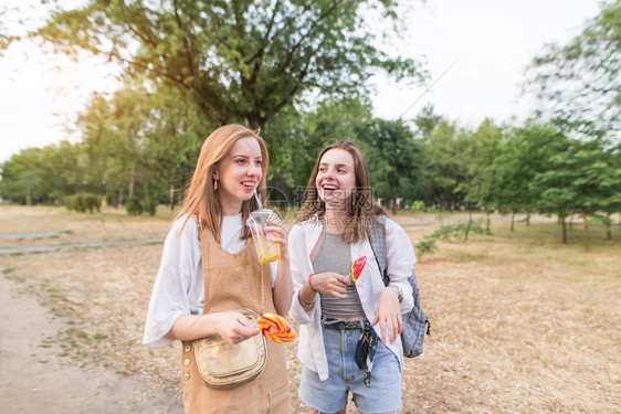 有吸引力的女孩用棒糖和柠檬水vv微笑的肖像在公园散步快乐时尚的女朋友图片