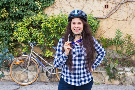 戴头盔的年轻女人在背景自行车和巷图片