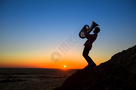 音乐剧Tuba的轮廓在令人惊叹的夕阳下背景图片