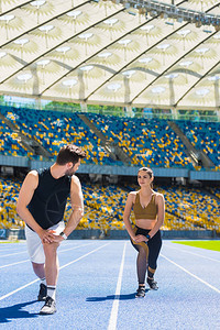 年轻运动夫妇在运动体育场跑步前先把腿加热图片