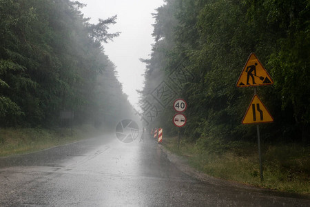 雨中汽车的行驶道路森林里有路标的荒凉道图片