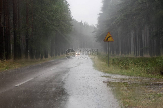 雨中汽车的行驶道路森林里有路标的荒凉道图片