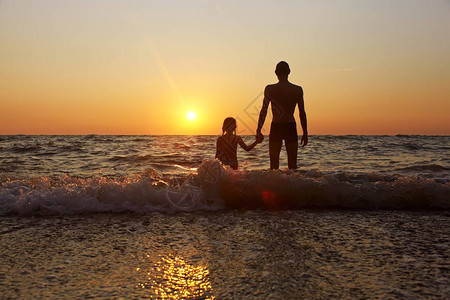 父亲和女儿崇拜海边的日落图片