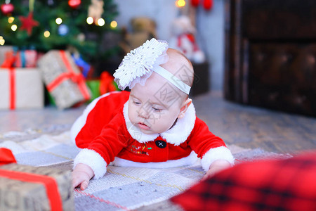 白种人女婴躺在圣诞树和礼物附近的地板上小孩的概图片
