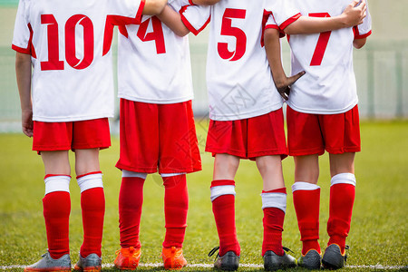 足球儿童队儿童足球替补球员站在一起排成一排年轻男孩的足球运动锦标赛四个孩子在球场上观图片