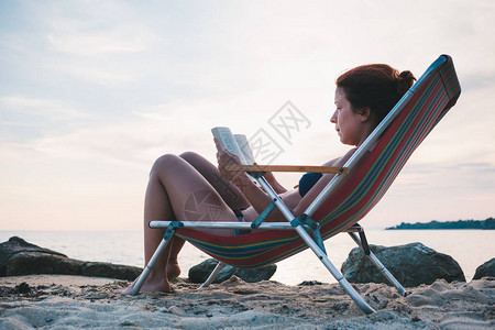 在海滩上看书的年轻女子图片