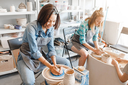 两个女朋友在陶工坊制作陶轮制作粘土手工艺品时微笑和交谈友图片