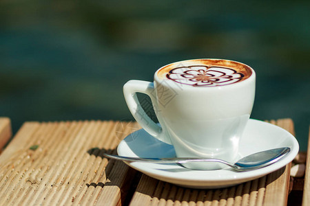 在海滩上孤立的卡布奇诺咖啡上的一杯艺术拿铁咖啡早上的咖啡带叶子的白图片