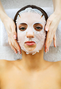 美丽美丽的女人在美容院戴着面具躺在按摩台上纯净清新的肌肤皮肤护图片