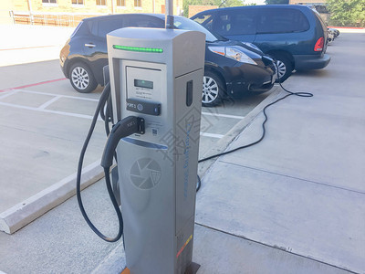 充电器插入电动汽车的特写充电站可充电池车辆在停车场加油未来汽车图片