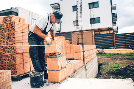 建筑工地的工匠用砖块和建筑墙做工图片