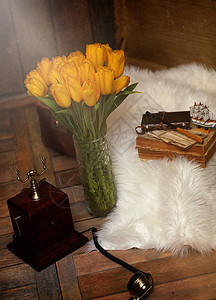 复古房间内部的花瓶里有一束黄色郁金香复古内饰与郁金香旧手机和图片