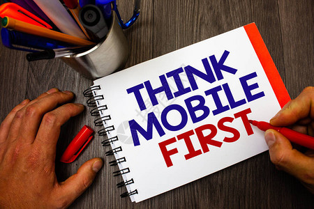 显示ThinkMobileFirst的文字符号概念照片手持设备首先设计营销目标便携式电话笔架记事本标记感受想法背景图片