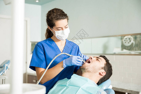 女牙医在诊所用牙科设备治疗中图片