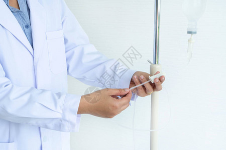 亚洲女医生在病房准备测试更换和调整输液瓶关闭有塑料注射器图片