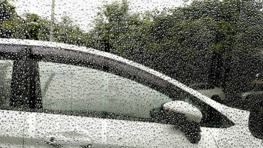 雨滴落在有汽车背景的窗户上图片