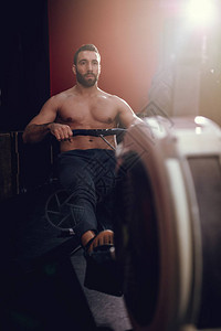 在健身房拉划船机的年轻肌肉男图片
