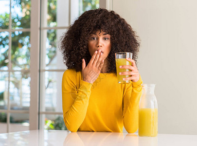 非裔美国妇女在家里喝健康果汁时用手顶嘴吃着健康的果汁图片