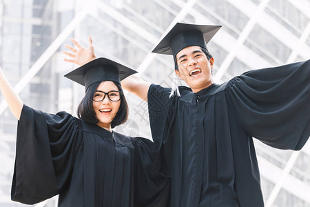 两个快乐的学生庆祝成功毕业在校园建筑背景的学图片