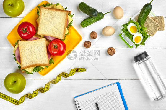 配有复制空间和健康早餐的顶级规划笔记本三明治加火腿和奶酪鸡蛋黄瓜番茄和白木图片