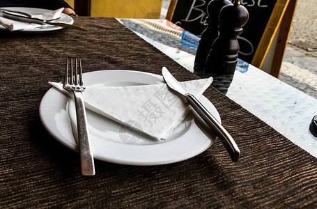白瓷盘刀叉餐巾纸硝石放在街边餐桌图片