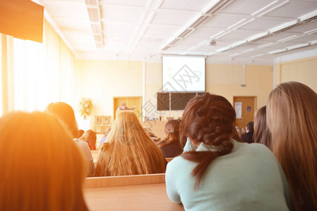 学生们坐在太阳光照耀的礼堂旁听和图片