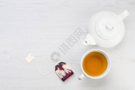 茶壶和茶包放在桌子上的一杯茶背景图片