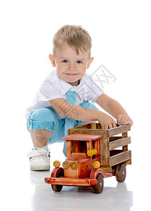 可爱的小男孩正在工作室里玩白色背景的玩具木车快乐童年家庭学习和教育背景图片