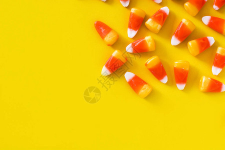 黄色背景上的典型的Halloween糖果玉米顶视图片
