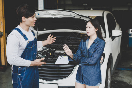 年轻机械师向女车主或汽车所有者谈论修理车的问题图片