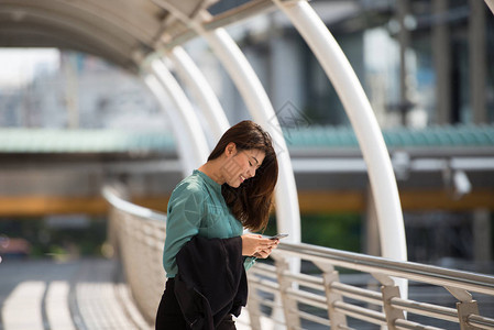 美丽的亚洲女商人在步行回家时使用移动电话图片