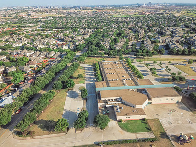 美国德克萨斯州欧文市住宅附近的鸟瞰学区小学被绿树环绕城市紧邻住宅区车道背景图片